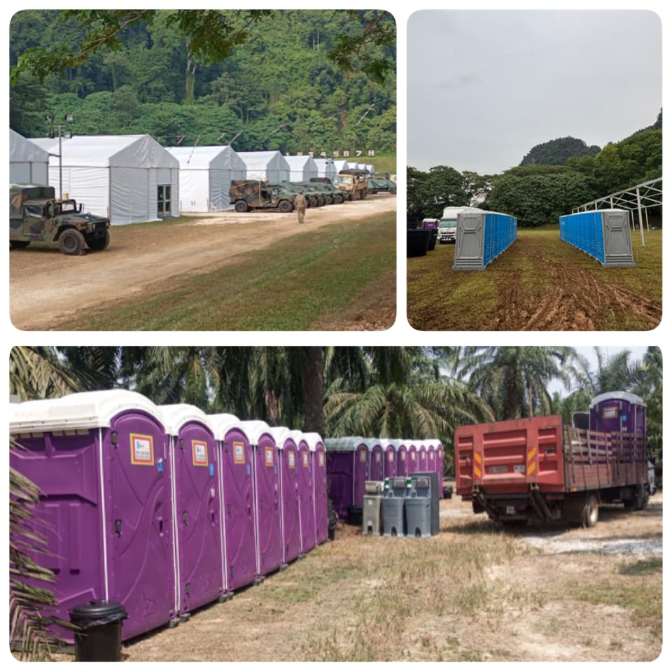 US Army training camp in Malaysia showing military tents with vehicles, blue and grey toilet blocks on grass, and a row of purple portable toilets with hand-wash stations